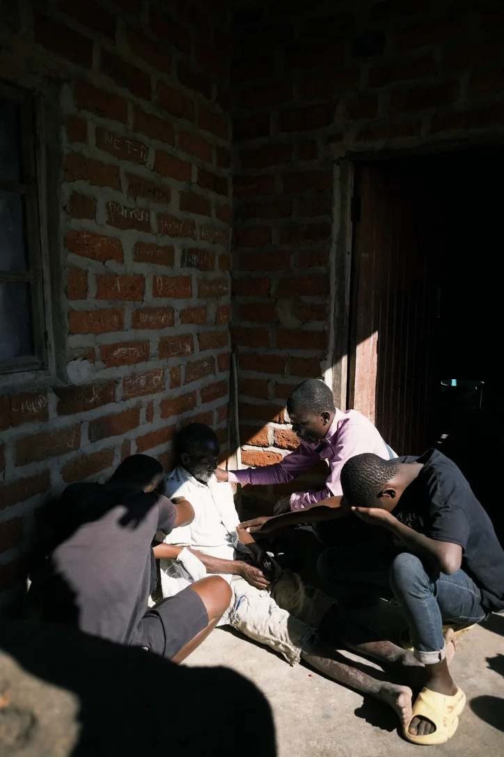 Three young people praying for an elderly man.