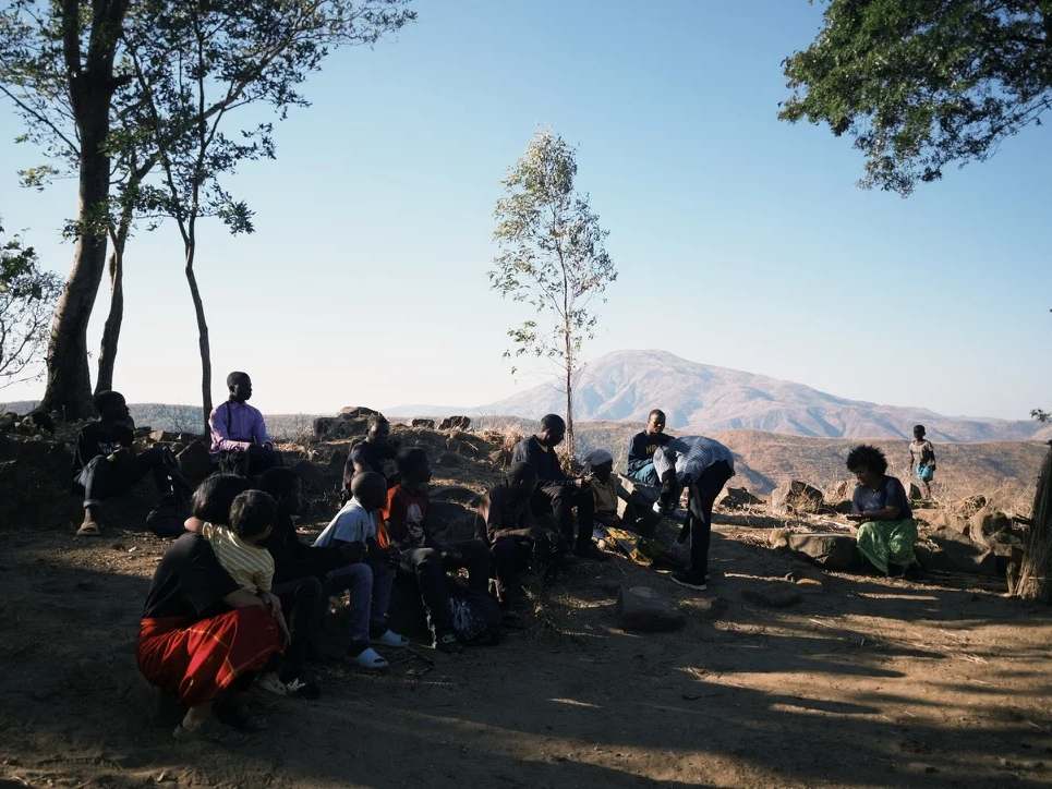 Young people and teenagers sitting and watching an elderly man being cared for